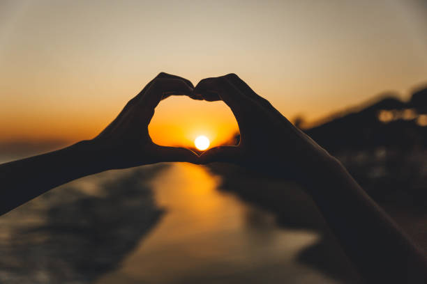 istock Hand in the shape of a heart during sunset 1296919240