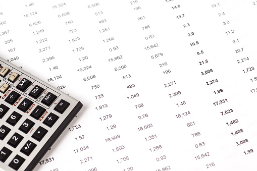 calculator and pen on sheet of financial data with numbers and charts