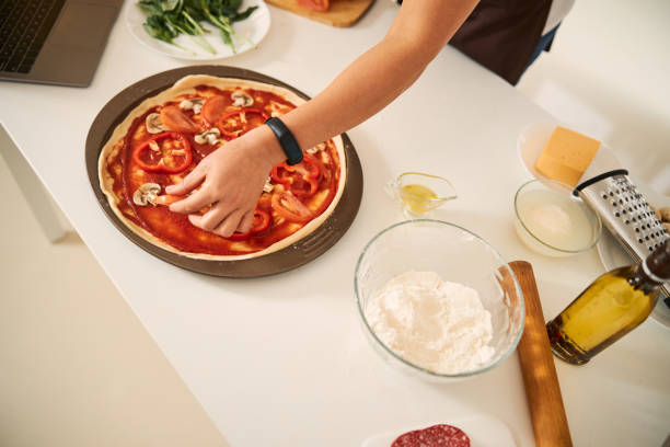 istock Covering pizza base with slices of vegetables 1296921670