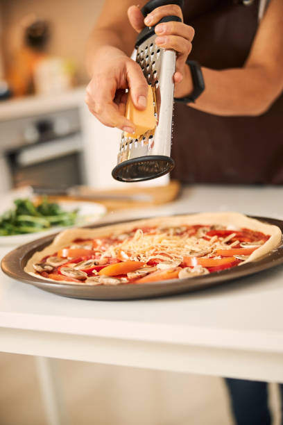 istock Grating cheese while cooking homemade pizza at home 1296921677