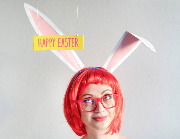 istock Young smiling woman in pink bunny ears on Easter day 1296923439
