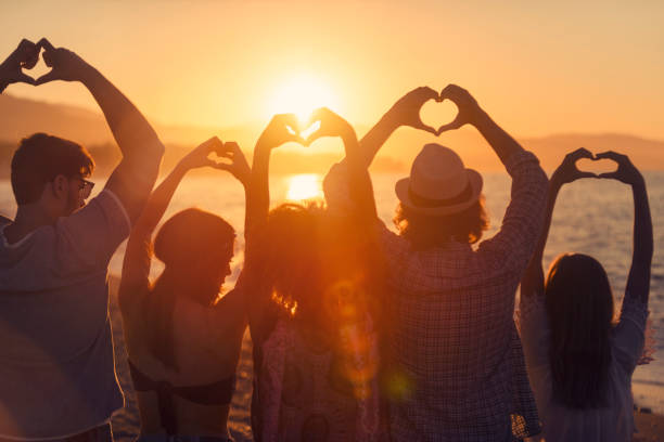 Group of young people making love heart signs at sunset. Group of young people making love heart signs at sunset. They are facing away from the camera and are in silhouette heart hands multicultural women stock pictures, royalty-free photos & images