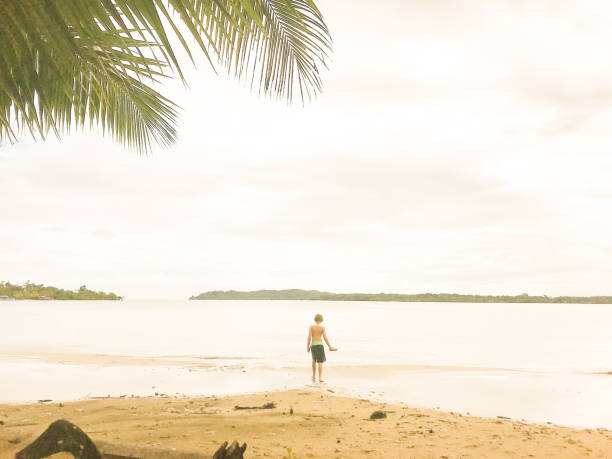 istock Child stands alone on a beautiful shoreline in Panama 1296931189
