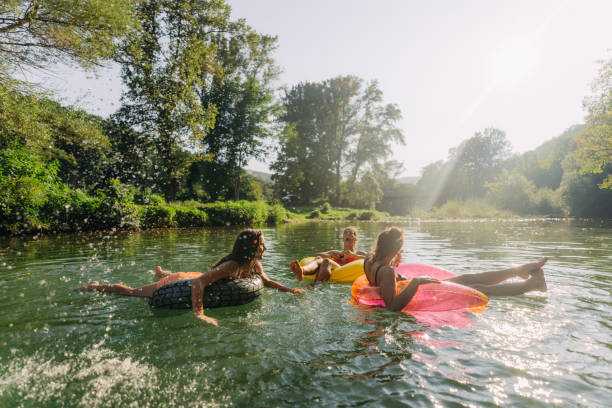 Best friends and summertime Photo of teenage girls swimming in the river while hanging out in nature; enjoying their youth and friendship and spending a hot summer day outdoors. inner tube stock pictures, royalty-free photos & images