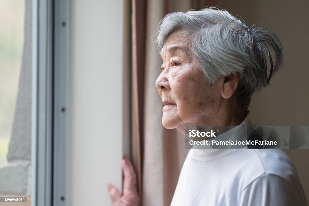 Serious Asian Senior Woman in 90s Looking Out of Window Chinese senior woman looking outside. Senior Adult Stock Photo
