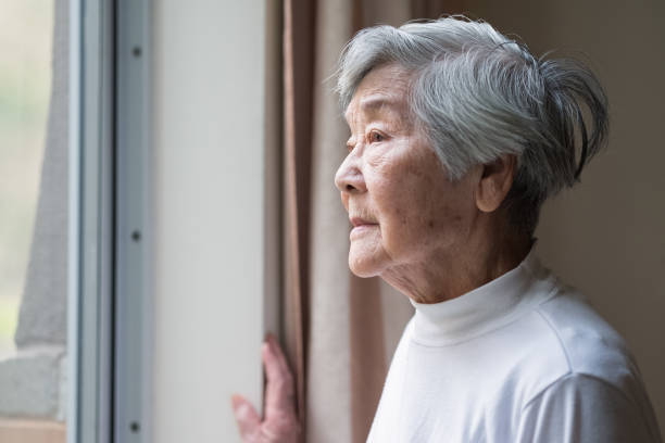 Serious Asian Senior Woman in 90s Looking Out of Window stock photo