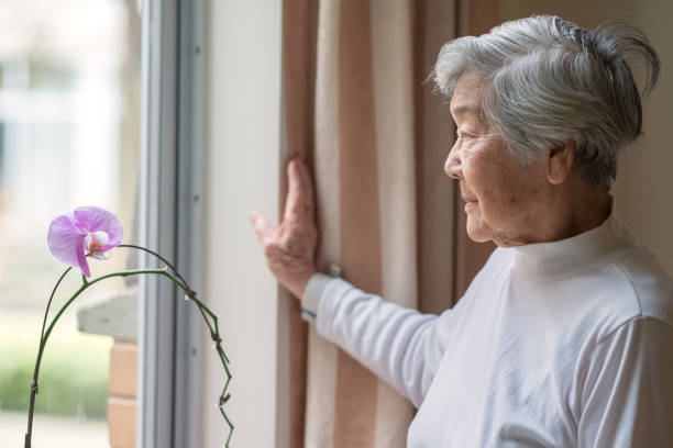 Portrait of Senior Asian Woman Looking out Window Asian senior woman in her 90s gazing out window. seasonal affective disorder stock pictures, royalty-free photos & images