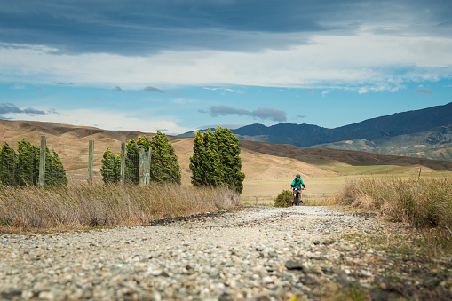 Tourist cycling the Otago Central Rail Trail in the strong wind, South Island, New Zealand