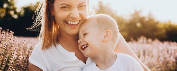 encantador hijo caucásico y su madre sonriendo en un campo de lavanda mirando a la cámara - worship place fotografías e imágenes de stock