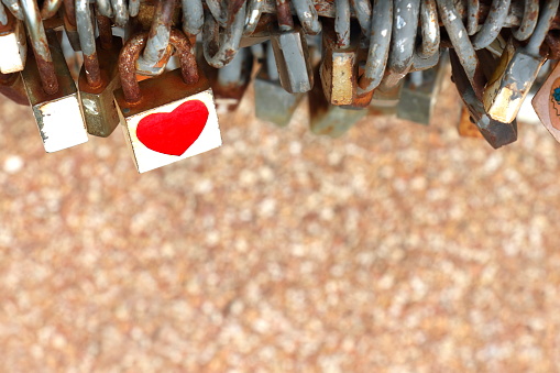 white key with red heart sticker and many old rust key lock with rust iron fence on blur brown background have copy space for put text