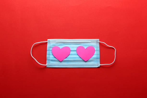istock Tri-layer protection mask for clinical use with pink hearts on a red background 1296961211