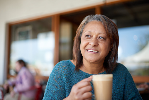 Shot of a mature woman having a cup of coffee at a cafe