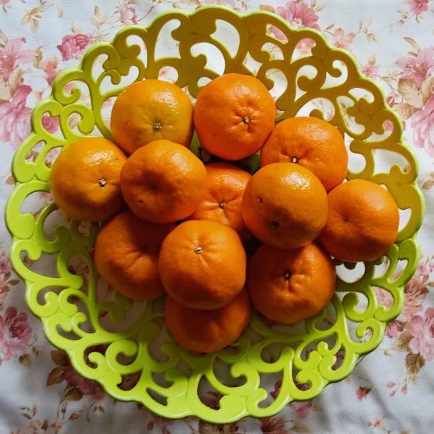 a pile of citrus fruit Pile of oranges on top of a large bowl patterned green joule stock pictures, royalty-free photos & images
