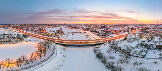 Bridge over a frozen river, a red brick buildings, buildings with turrets and lancet windows and some Orthodox churches at the center of the city. A panoramic aerial view, winter, sunset. Yoshkar-Ola, Volga region, Russia