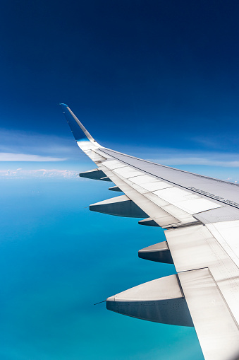 image taken from airplane window with wing with blue tip and blue background sky