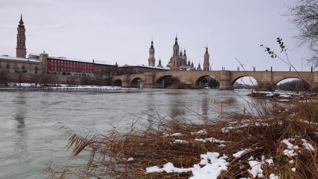 Panoramic view of Zaragoza, Basilica del Pilar and Ebro river. Remains of snow. Cormorants in the river