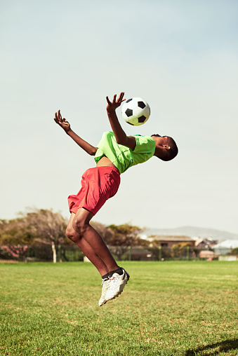 Shot of a young boy playing soccer on a sports field