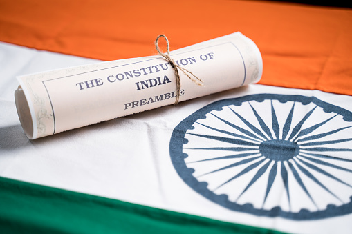 Selective focus on flag, Indian constitution or Bharatiya Savidhana preamble old scattered text paper placed on Indian flag - Concept of Freedom, Nationality and patriotism.