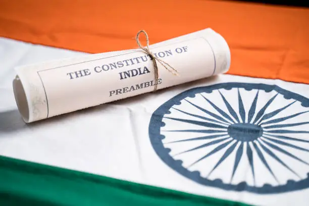 Selective focus on flag, Indian constitution or Bharatiya Savidhana preamble old scattered text paper placed on Indian flag - Concept of Freedom, Nationality and patriotism