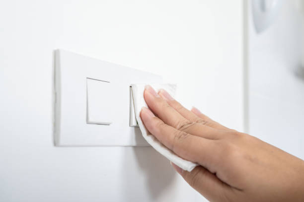 istock Coronavirus COVID-19 prevention cleaning tissue paper wet wiping switch button with antibacterial disinfecting wipe for killing corona virus on touching surface 1296965127