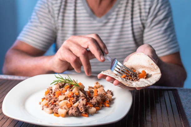 uomo che mangia carne con verdure e tortilla - carnivore foto e immagini stock