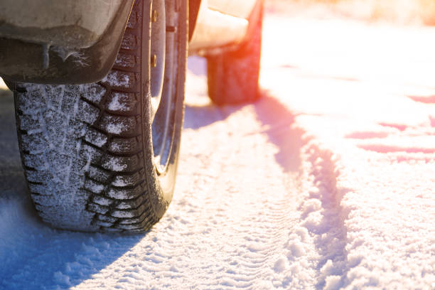 istock Studded winter car tires on snow-covered road 1296972452