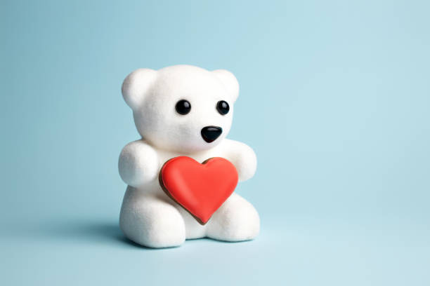 istock White teddy bear holding a heart shaped cookie on pastel blue background 1296974466