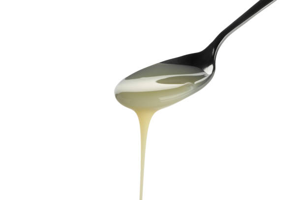 istock Spoon with dripping condensed milk isolated on white background 1296978634