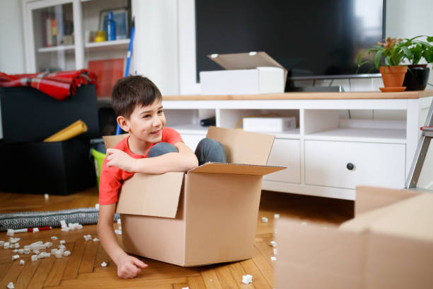 istock Boy sitting in small cardboard box and having fun during house move 1296982515
