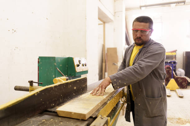 istock Male carpenter using saw for cutting wood at workshop 1296983280