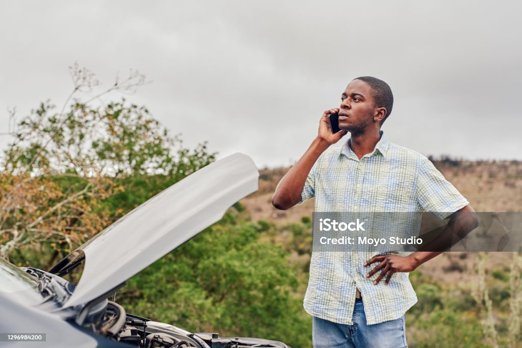 Can you please come tow my car away Cropped shot of a handsome young man calling roadside assistance while standing next to his broken down car outdoors Car Stock Photo