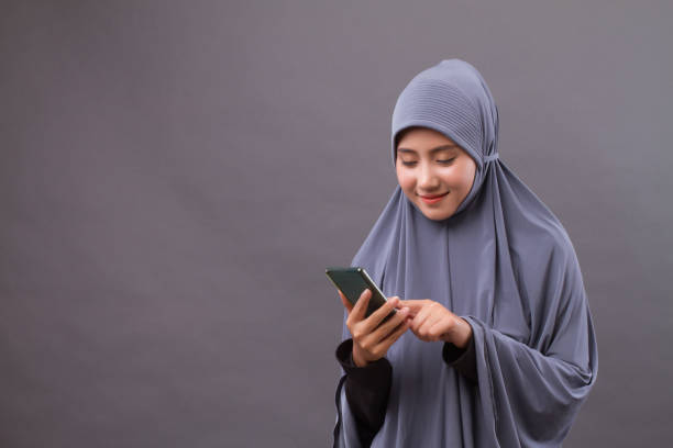 istock happy smiling muslim woman using smartphone, wireless internet device 1296987422