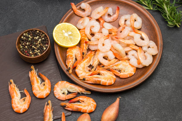 istock Shrimp in ceramic plate. Allspice and rosemary sprigs on table. 1296987677