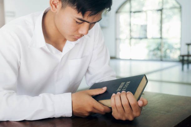 istock Man praying, hands clasped together on her Bible. 1296987967
