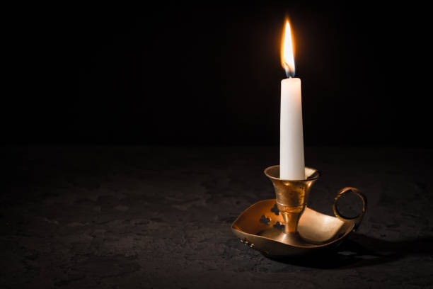 istock Burning candle  in vintage candlestick on black background 1296989844