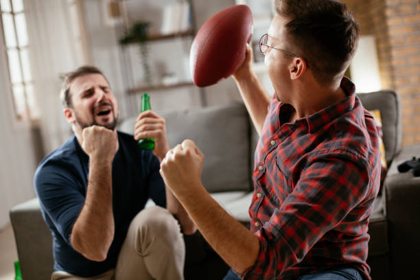 istock Men drinking beer and watching sports game on tv 1296991007