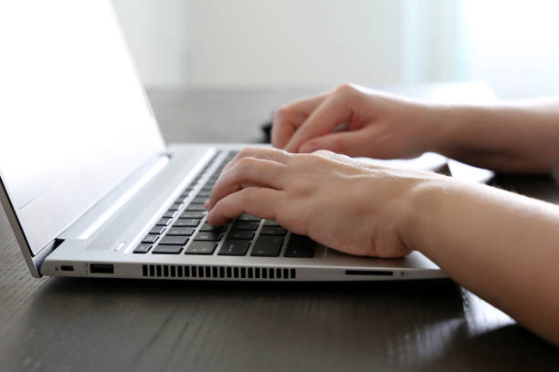 istock Female hands on laptop keyboard on a desk in sunlight 1296995020