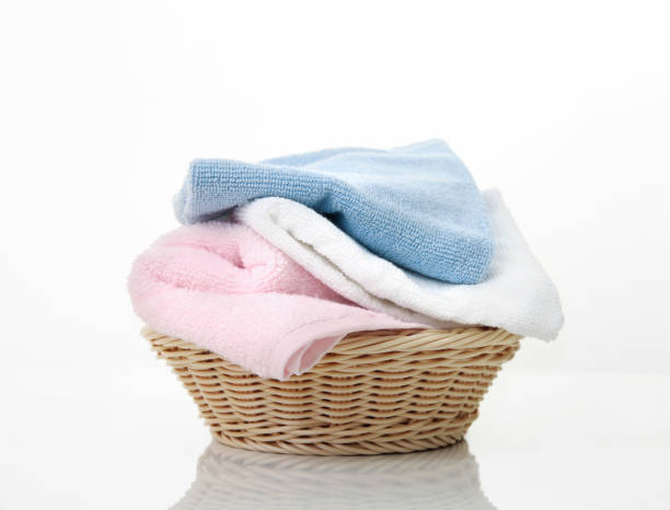 istock Folded towels stack in basket on white background,heap of colorful laundry on table. 1296995469