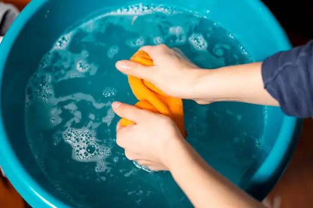 Womans hands are washing a cleaning cloth in a washbowl in her house.