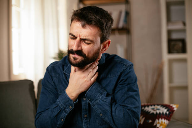 istock Young man sitting on sofa having fever. 1296996978