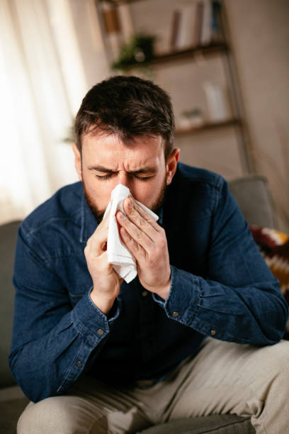 istock Young man sitting on sofa having fever. 1296997089