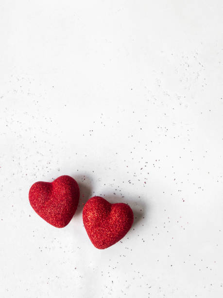 istock Two red shiny hearts on a gray background. 1296998931