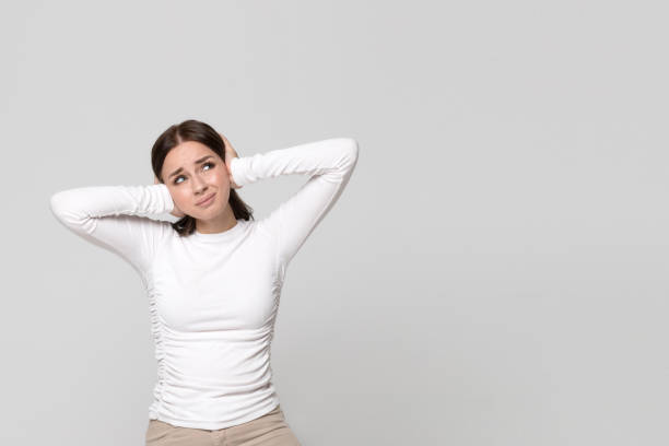 istock Angry stressed female covering her ears, looking up, having headache problems with noise from the neighbors above 1296999597