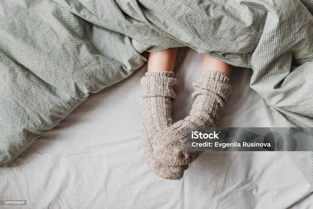Atmospheric picture about the comfort From under the blanket you can see children's feet with warm wool socks. Sock Stock Photo