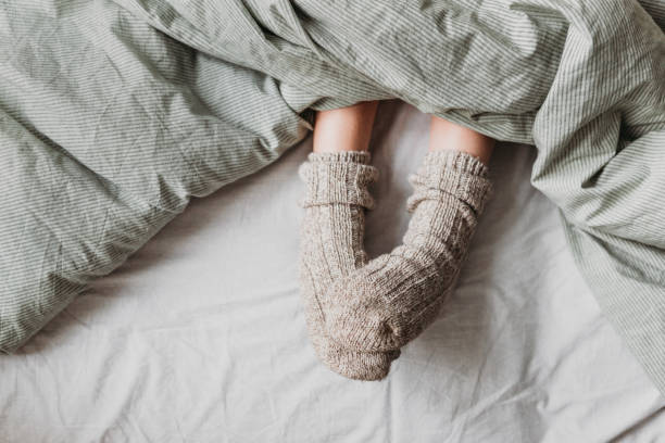 Atmospheric picture about the comfort From under the blanket you can see children's feet with warm wool socks. sock stock pictures, royalty-free photos & images