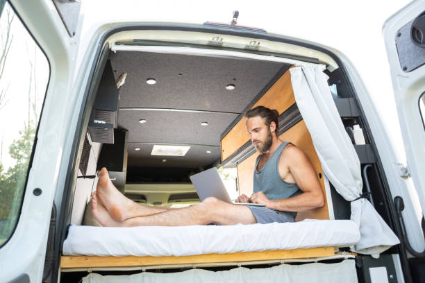istock Young man with a laptop inside his camper van 1297001190