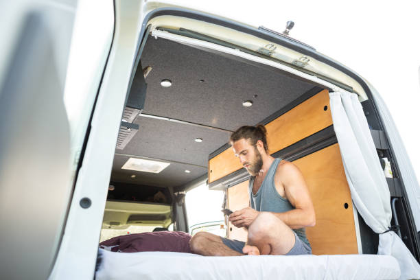 istock Man sitting in his camper van using a smartphone 1297001231