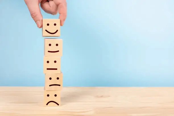 Photo of Customer service evaluation and satisfaction survey concepts. client's hand picked happy face smile face symbol on wooden blocks, copy space