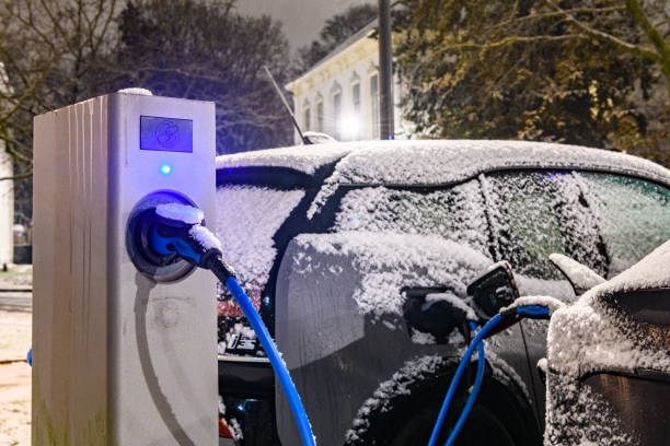 voitures électriques chargeant à une station de recharge de véhicule électrique pendant une nuit froide d’hiver neigeuse - third generation photos et images de collection