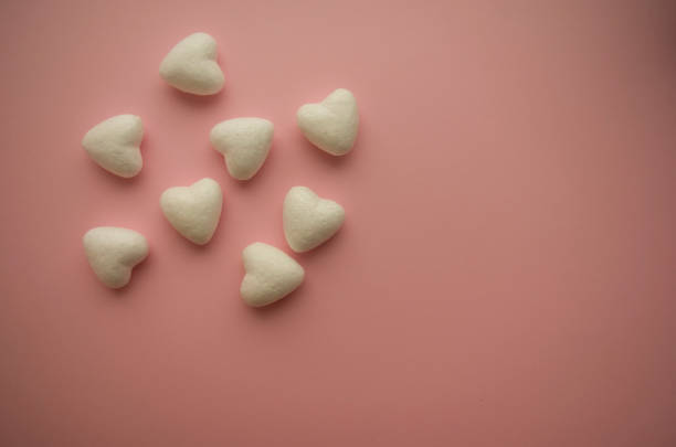 istock Small voluminous white hearts are scattered on the left on a pink background 1297003699